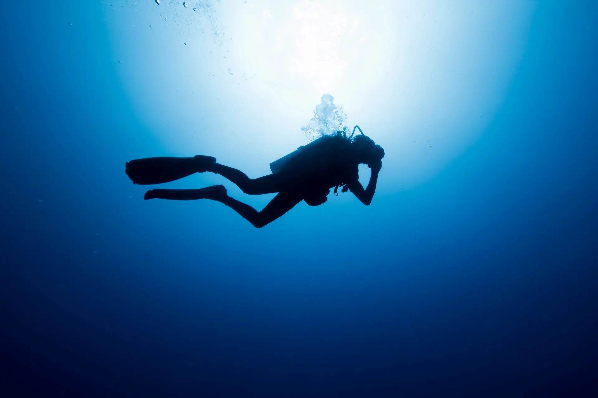 Image horizontale représentant une plongeur loisir en vue de coté dans une ambiance sombre. Utilisé dans la page Baptême